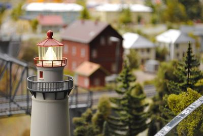 Tilt shift image of illuminated lighthouse against buildings