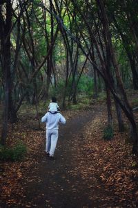 Rear view of man walking on footpath in forest