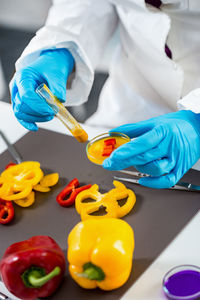 Midsection of scientist experimenting on bell peppers