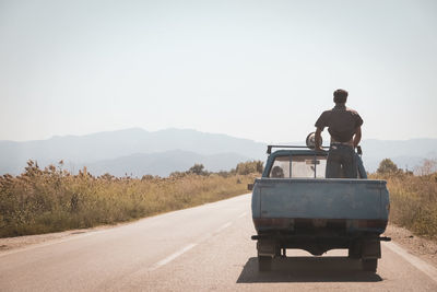 Rear view of man on road against clear sky