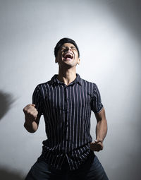 Young man looking away while standing against wall