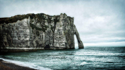 Rock formation in sea against sky