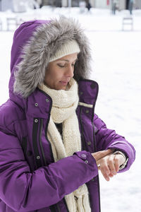 Young woman watching time in snow