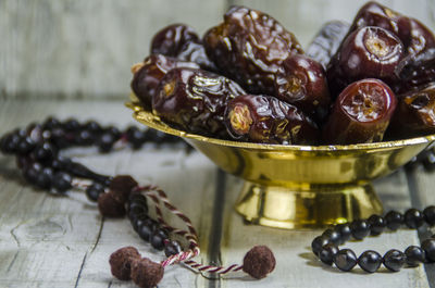 Dried date in a golden bowl on wooden background - prayer beads - concept for ramadan.