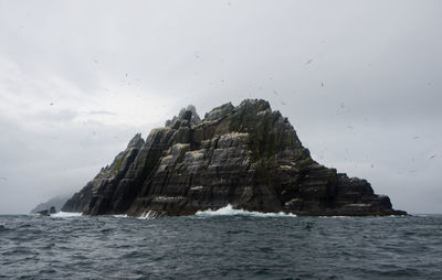 Rock formations by sea against sky