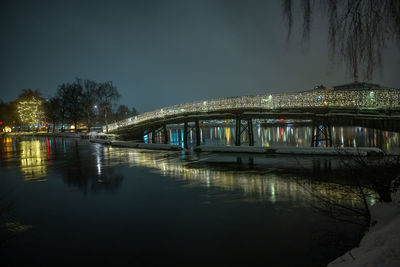 Illuminated bridge over river against sky at night