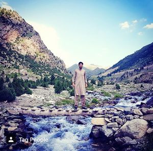 Man standing on rock by mountain against sky