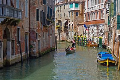 People in canal amidst buildings in city