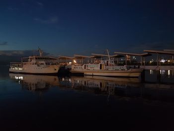 Boats moored at harbor against sky at night