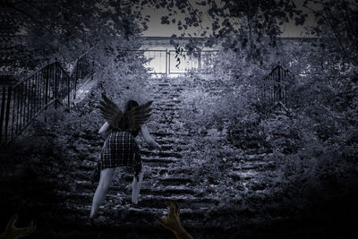 Rear view of woman standing by plants