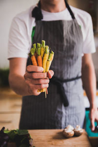 Midsection of man holding mini carrots