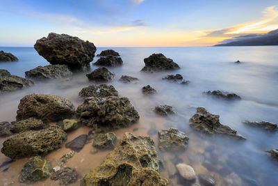 Scenic view of rocks in sea during sunset