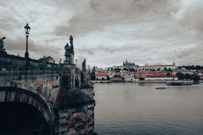 Buildings by sea against cloudy sky