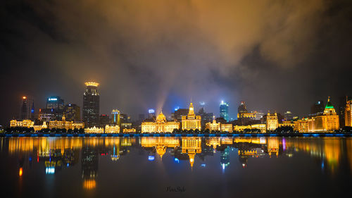 Illuminated city buildings against sky at night