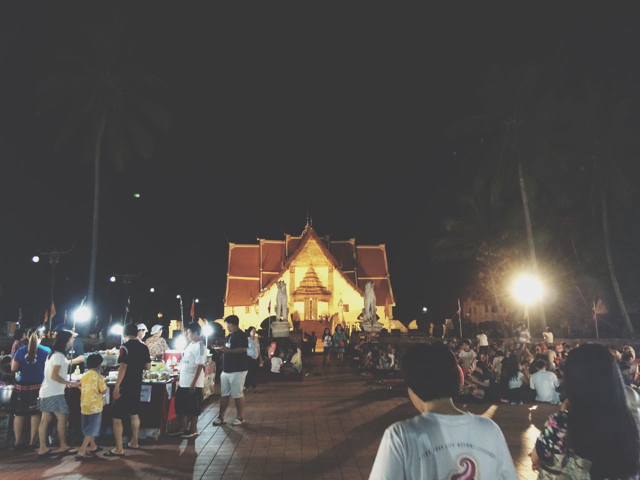 lifestyles, illuminated, large group of people, men, person, religion, place of worship, night, spirituality, leisure activity, architecture, built structure, building exterior, clear sky, mixed age range, lighting equipment, church, rear view