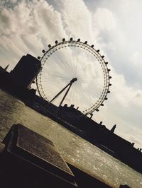 Low angle view of ferris wheel against cloudy sky