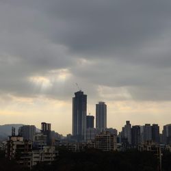 Modern buildings in city against sky during sunset