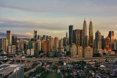 Aerial view of buildings in city against cloudy sky