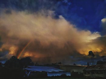 Silhouette houses and buildings against sky at sunset