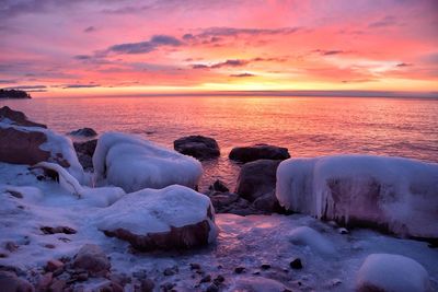 Scenic view of sea against dramatic sky during sunset