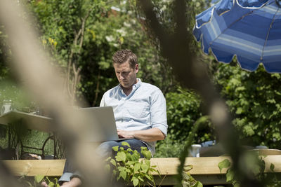 Mid adult man using laptop on terrace