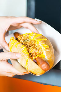 Cropped hand of woman holding freshly prepared hotdog.