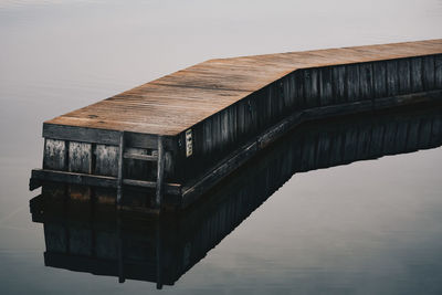 Reflection of bridge in lake against clear sky