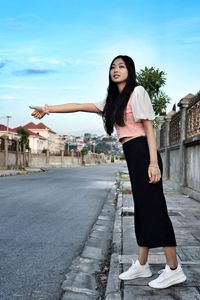 Full length of young woman standing in front of building