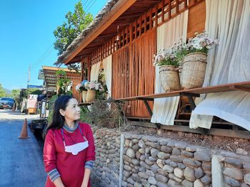 Portrait of young woman standing against building