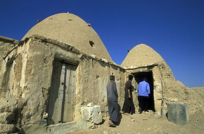 Men entering abandoned adobe house