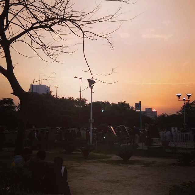 sunset, silhouette, tree, sky, bare tree, street light, building exterior, built structure, architecture, city, orange color, men, cloud - sky, dusk, nature, branch, lifestyles, leisure activity, outdoors