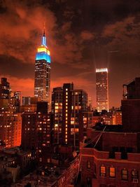 Illuminated cityscape against cloudy sky