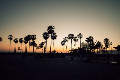 Silhouette palm trees on beach against clear sky at sunset