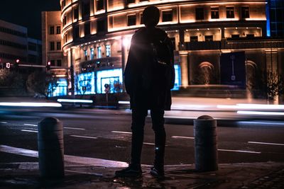 Rear view of man on city street at night