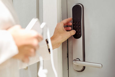 Cropped image of woman opening electric lock on silver door