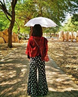 Rear view of woman standing by trees