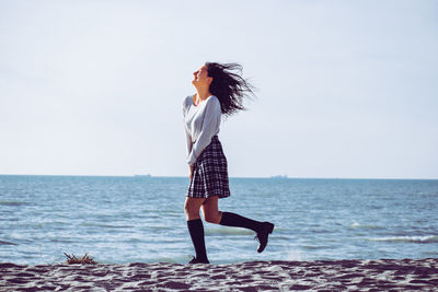 Woman standing by sea against sky