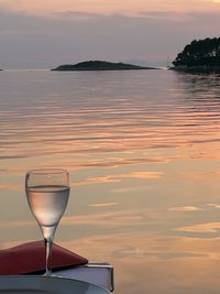 Wineglass against sea during sunset