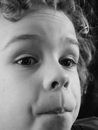 Close-up of boy looking away against black background