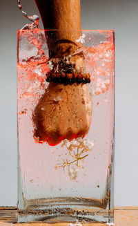 Close-up of hand splashing drink in jar on table