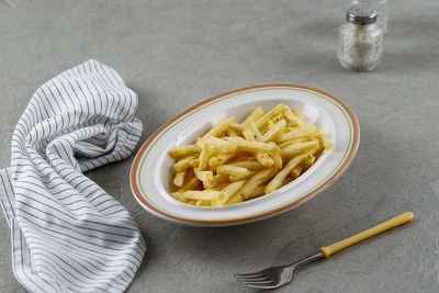 French fried on ceramic plate with salt and pepper on cement background, copy space for text