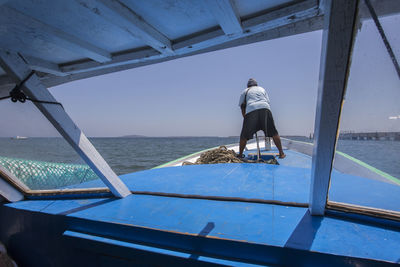 Rear view of man sitting on boat against sky