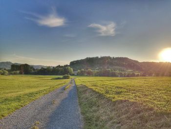 Road amidst field against sky