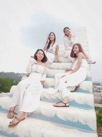 Portrait of women sitting on staircase against sky