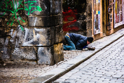 Man kneeling by graffiti wall