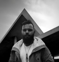 Portrait of young man standing against built structure