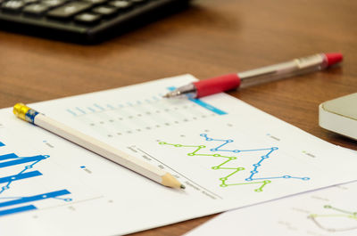 Close-up of pencil and pen on graph papers at office desk