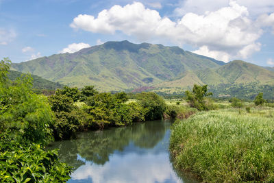 Scenic view of green landscape and mountains against sky