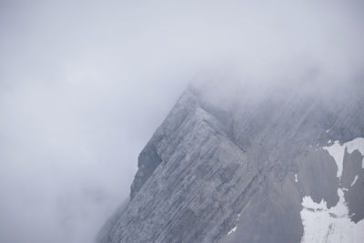 Scenic view of snowcapped mountains against clouded sky