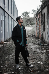 Young man looking away while standing on building